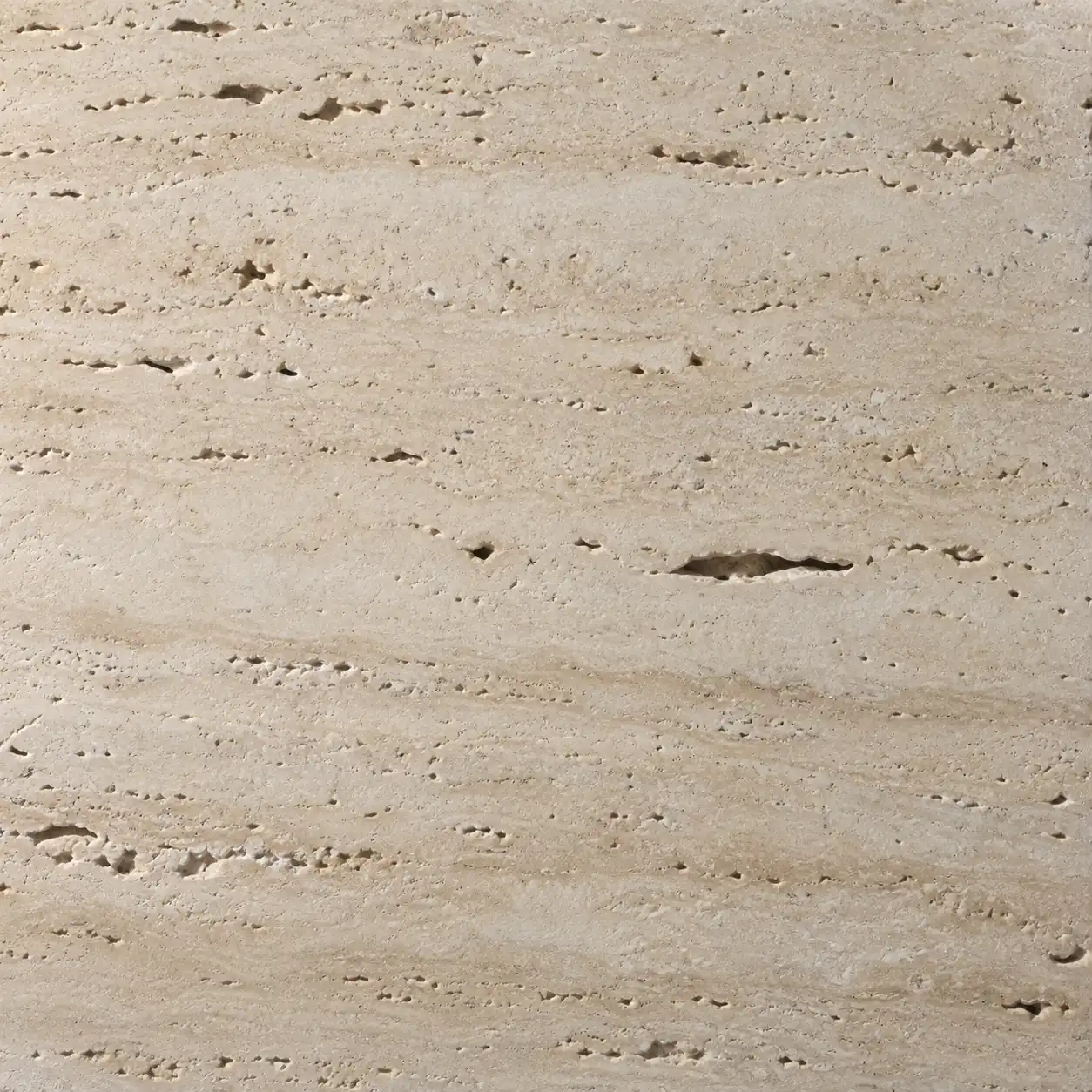 Close detail of honed travertine, its open pores catching the light